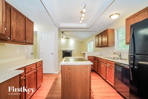 A kitchen with wooden cabinets and a black refrigerator.