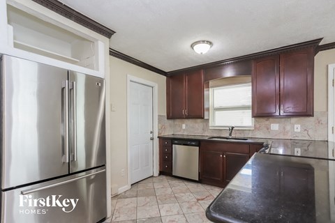 A kitchen with a stainless steel refrigerator and wooden cabinets.