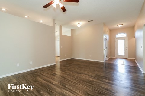 A spacious room with wooden floors and a ceiling fan.