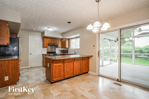A kitchen with wooden cabinets and a black fridge.