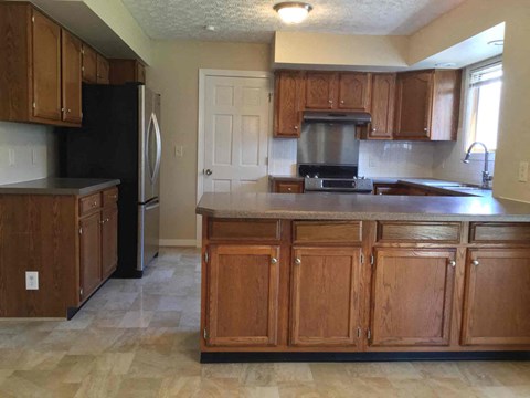 A kitchen with wooden cabinets and a black refrigerator.