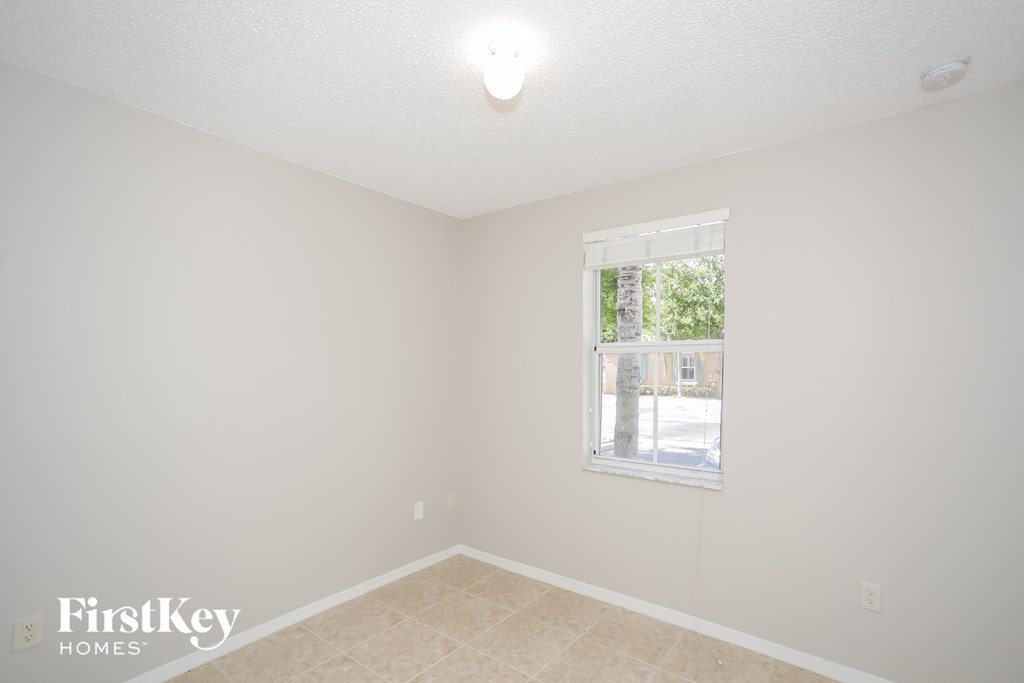 a bedroom with a window and a tile floor