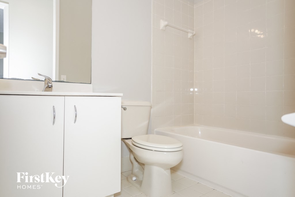 a white bathroom with a toilet and a bath tub