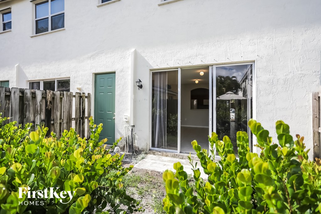 the outside of a white house with a green door and plants