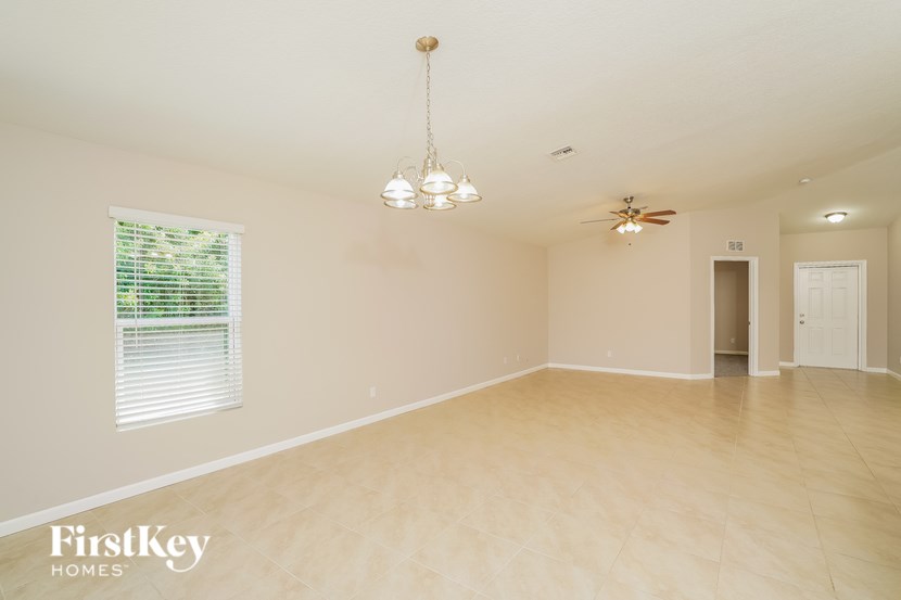 A spacious room with wooden flooring and a chandelier hanging from the ceiling.