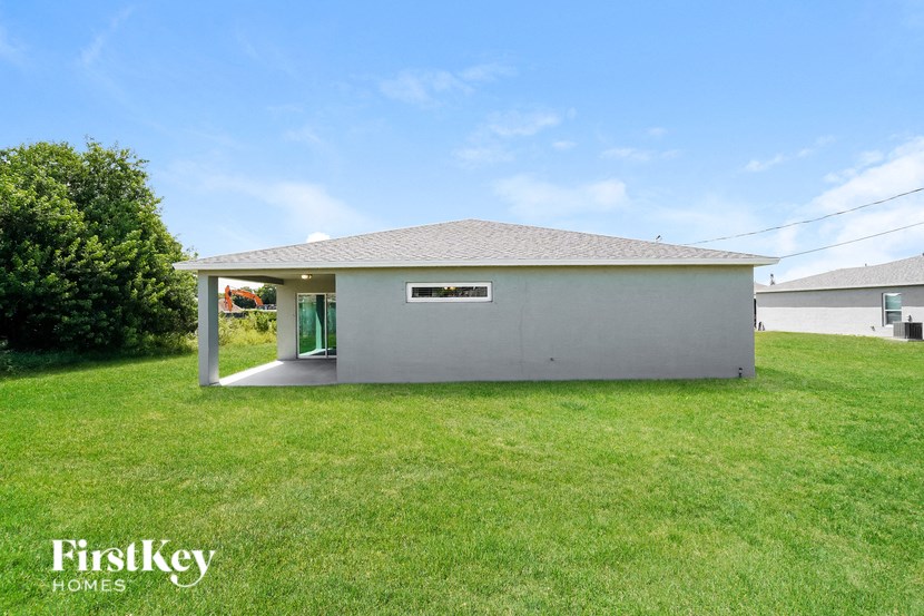 A small white building with a green door is situated in a grassy area.