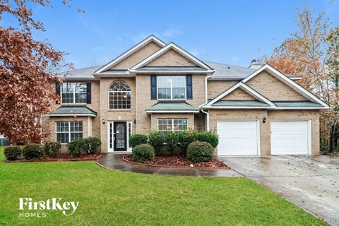 a brick house with two garage doors and a lawn