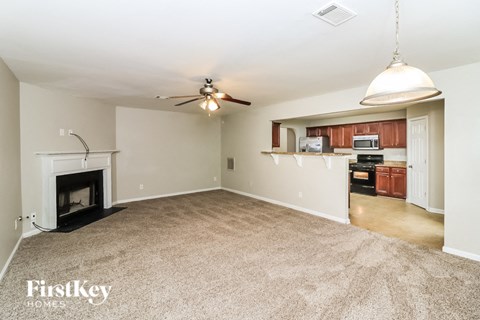an empty living room with a fireplace and a ceiling fan