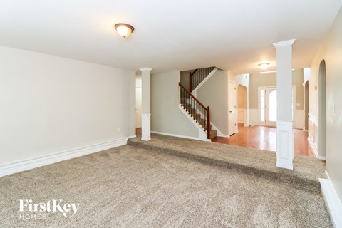 a living room with a carpeted floor and a staircase