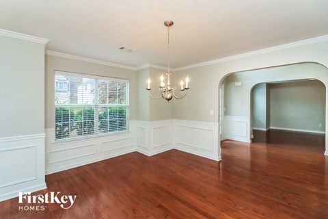 an empty dining room with a large window and a chandelier