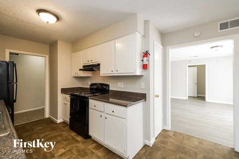 A kitchen with white cabinets and a black fridge.