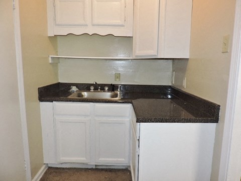 A kitchen with white cabinets and a black countertop.
