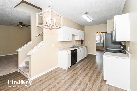 a kitchen with white cabinets and black appliances and a chandelier