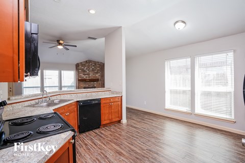 A kitchen with a stove top oven and wooden floors.