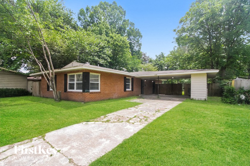a brick house with a lawn and a driveway