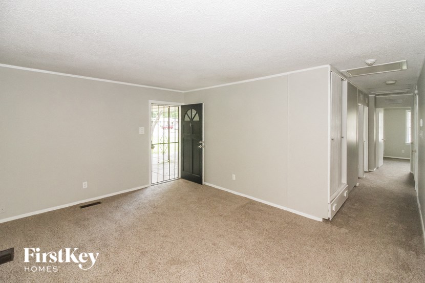 an empty living room with a door to a hallway