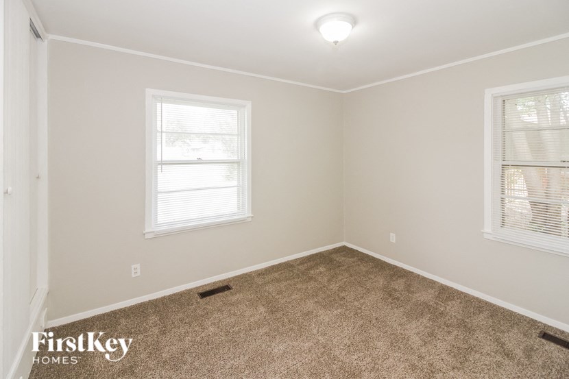 a bedroom with a carpeted floor and two windows