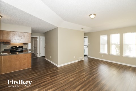 A spacious room with wooden floors and a kitchen area with a stove top oven.