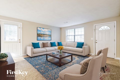 A living room with a couch, chairs, and a painting on the wall.
