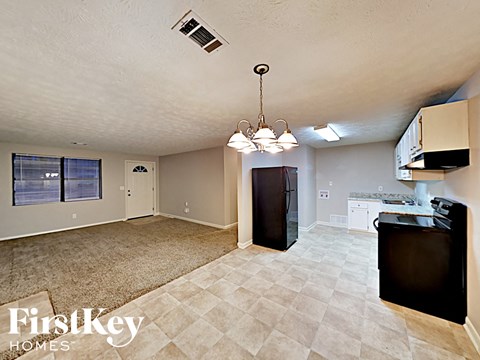 A kitchen area with a black fridge and a black TV on the counter.