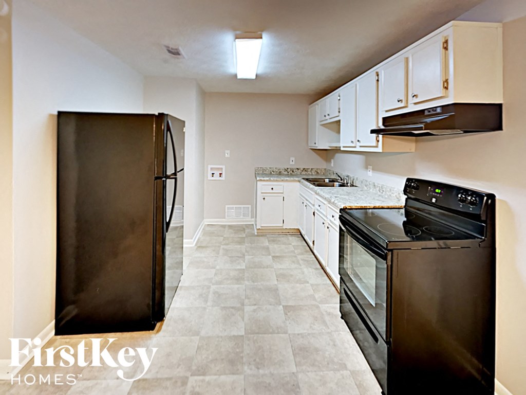 A kitchen with a black fridge and black oven.