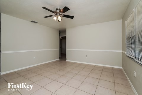 an empty living room with a ceiling fan and tiled floors