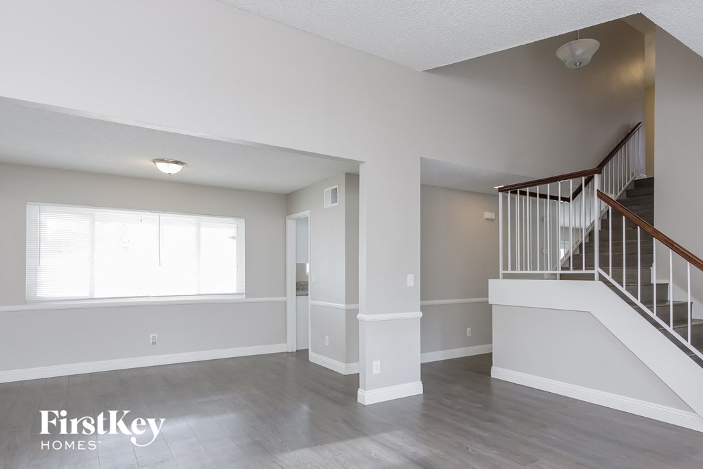 A spacious living room with a staircase and a window.