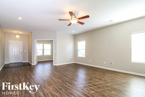 A spacious room with wood flooring and a ceiling fan.