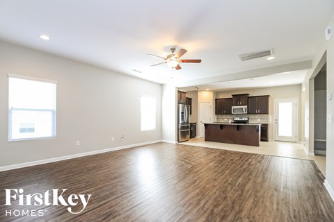 A spacious living room with wood flooring and a ceiling fan.