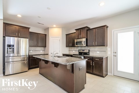 A modern kitchen with a stainless steel refrigerator and a granite countertop.