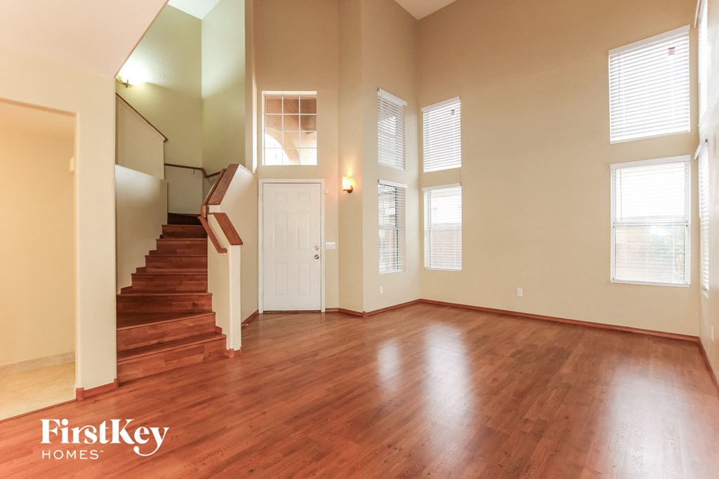 an empty living room with wood floors and a staircase