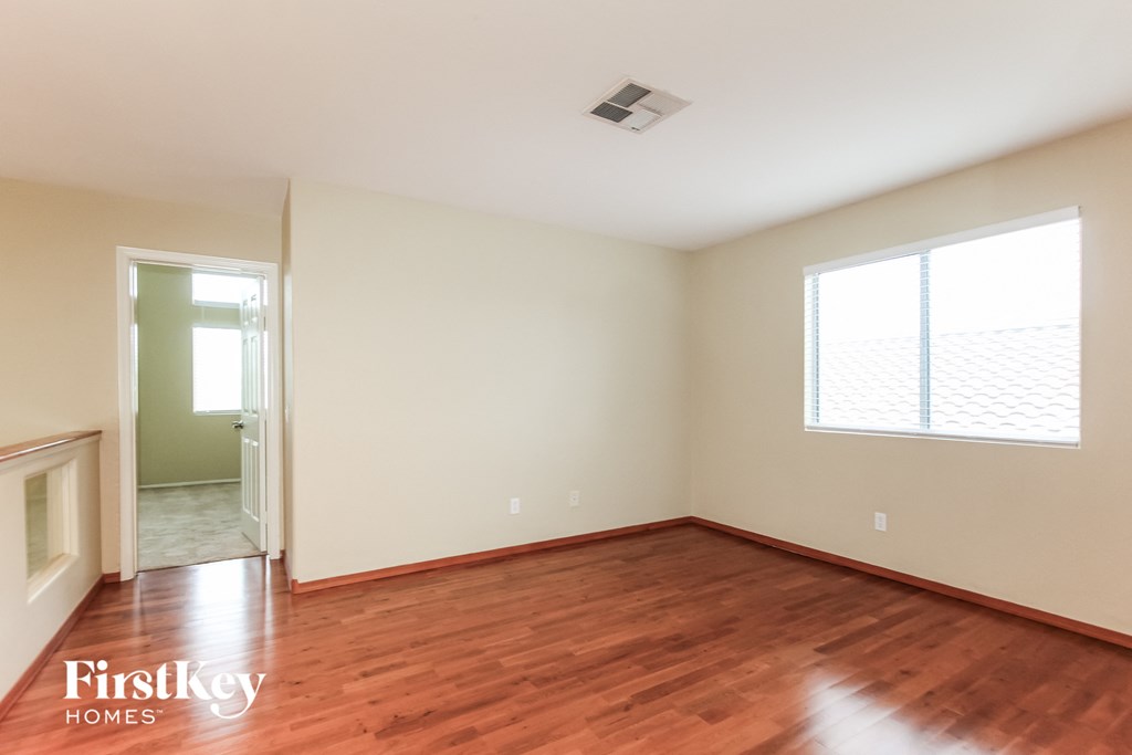 a living room with wood floors and white walls and a window