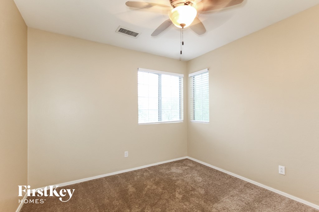 a bedroom with a ceiling fan and two windows