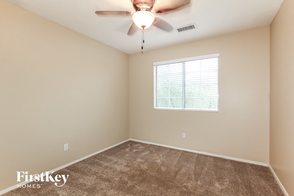 an empty room with a ceiling fan and a window