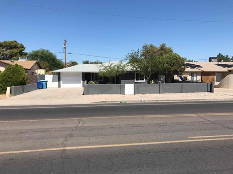 a house with a fence on the side of a street
