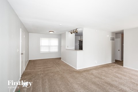A spacious room with a carpeted floor and white walls.