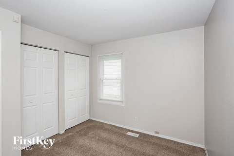 A room with a carpeted floor and two doors.