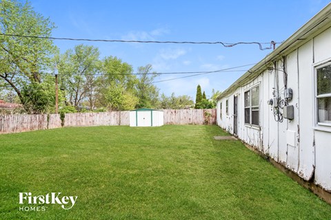 A white house with a fence and a green lawn.