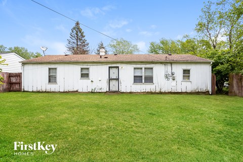 A white house with a brown roof and a green lawn in front.