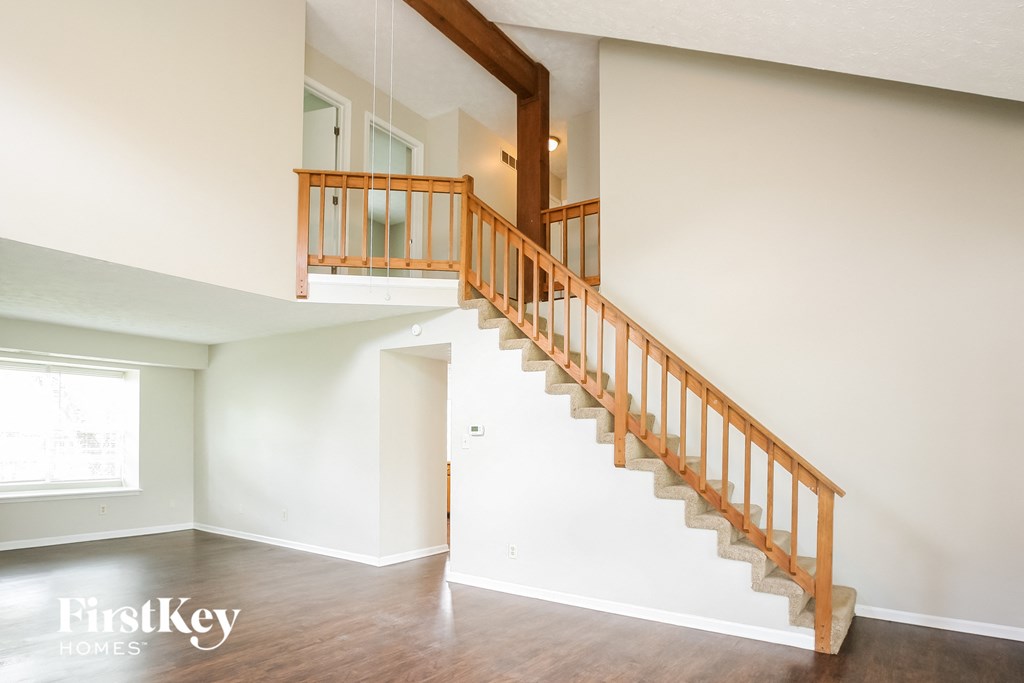 A wooden staircase with a railing in a white room.