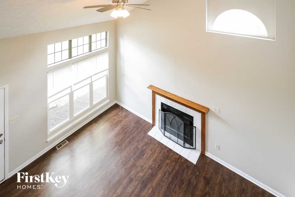 A living room with a fireplace and a ceiling fan.