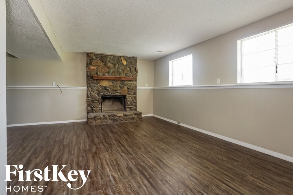 A room with a stone fireplace and wooden flooring.