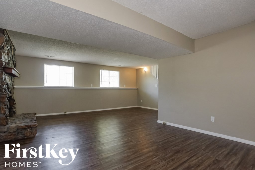 A room with wooden floors and a stone fireplace.