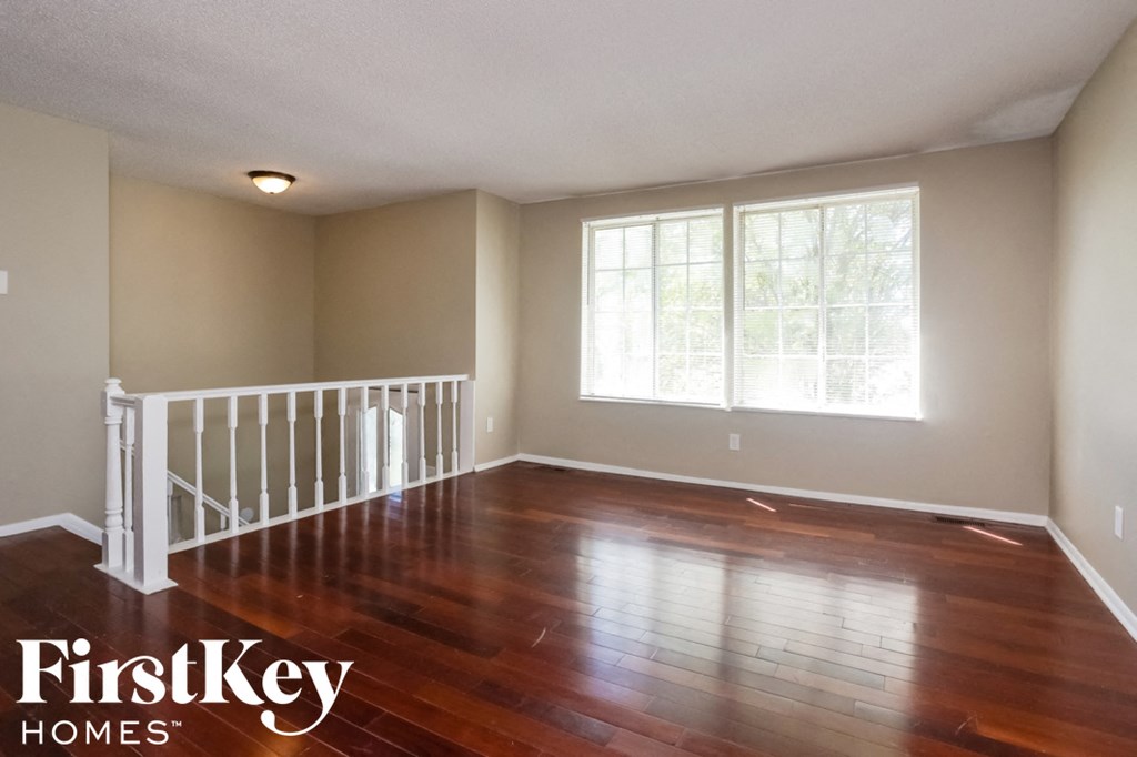 Empty room with wooden floors and white railings.