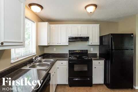 A kitchen with black appliances and white cabinets.