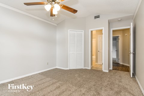 a spacious living room with carpet and a ceiling fan