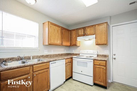 a kitchen with wooden cabinets and white appliances and a window