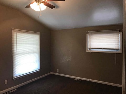 a bedroom with two windows and a ceiling fan