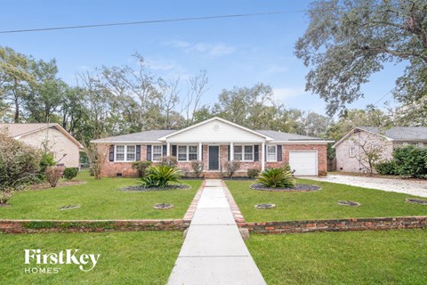 A house with a white front yard and a brick wall.