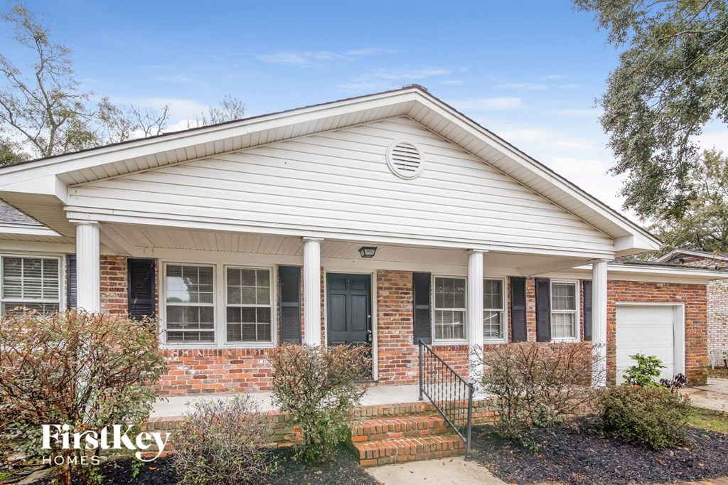 A house with a white front porch and a brick wall.
